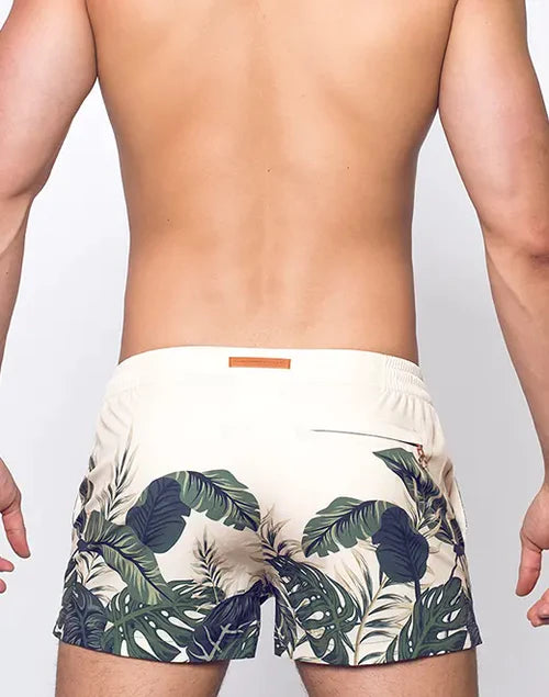 Beige s50 print swim shorts with vibrant green and dark blue tropical leaf pattern for beachside adventures