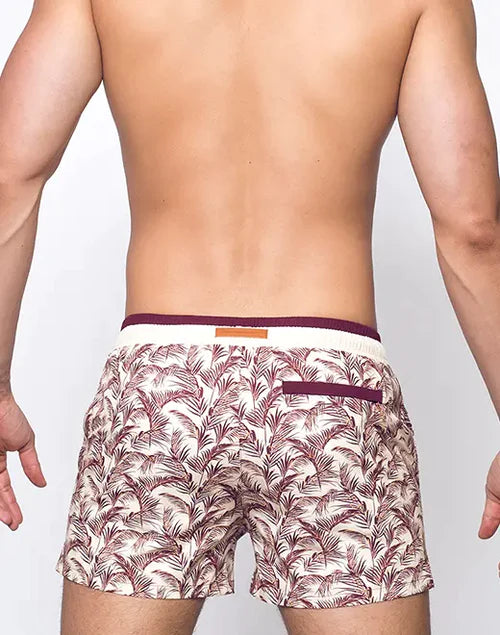 Beige swim trunks with a maroon palm leaf pattern and matching waistband perfect for beachwear