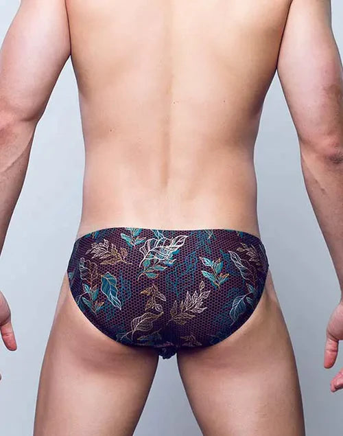Dark navy vb20 blk label swim trunks with intricate teal and gold leaf pattern and sheer mesh overlay