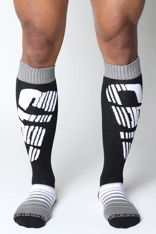 Black and white velocity 2.0 knee high socks with bold skull design and gray ribbed cuffs for athletic use