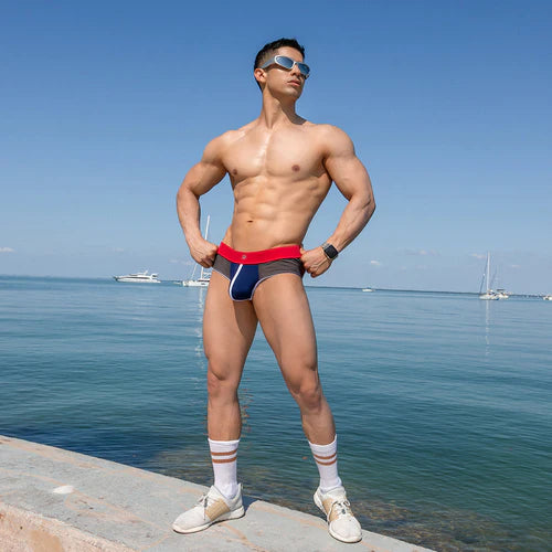 Men’s red and navy blue swim trunks with a bold athletic design featured in pistol pete ppe034 piping bulge pouch jockstrap article