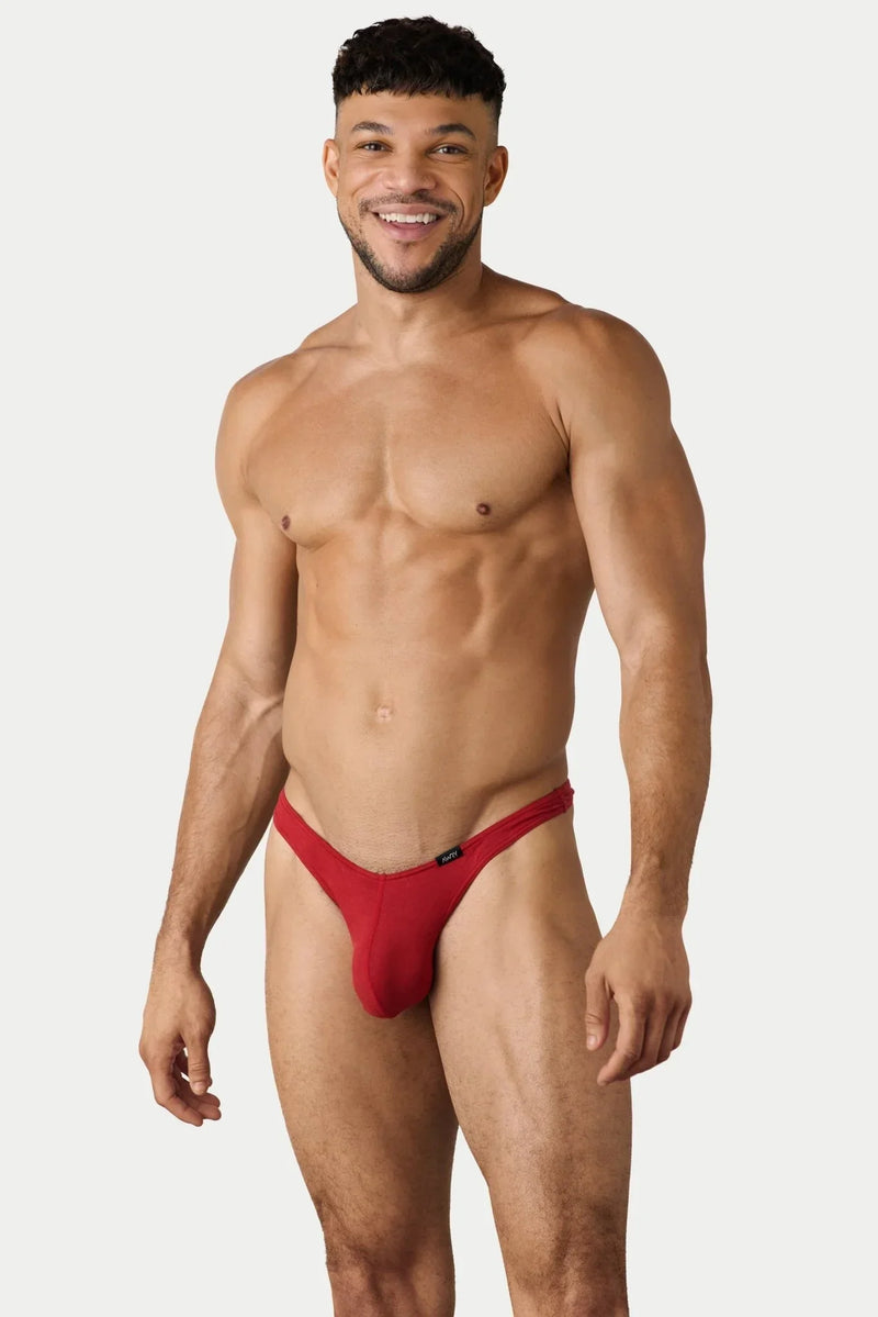 Red minimalist mens thong on a smiling muscular male model in a clean studio setting