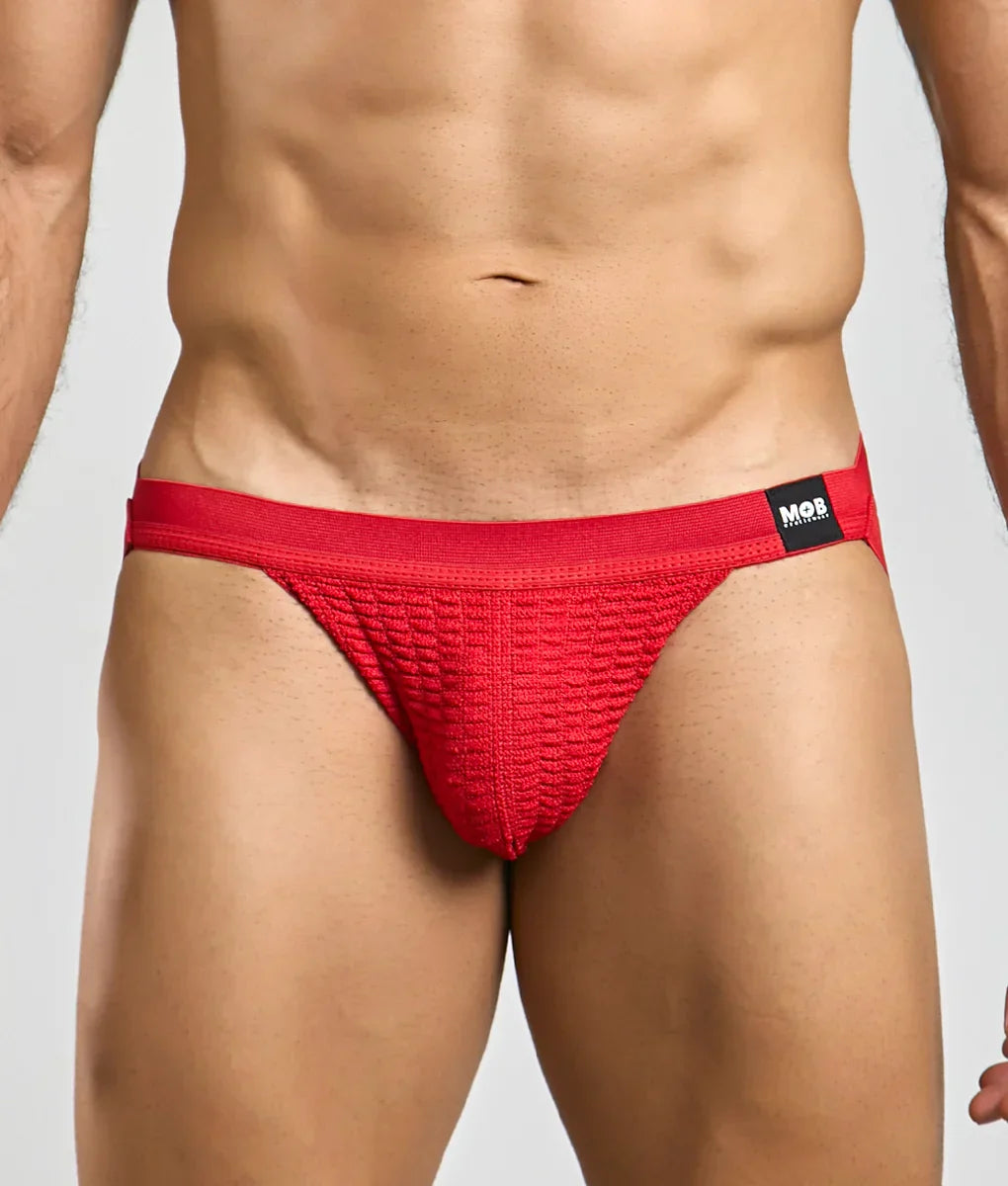 A torso wears a textured red jockstrap with elastic straps on white.