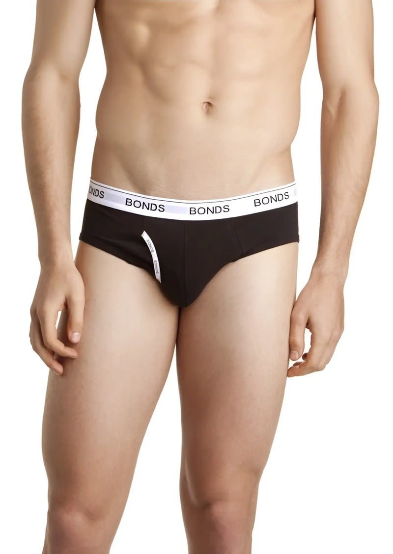Torso of a man wearing black briefs with a white waistband background.