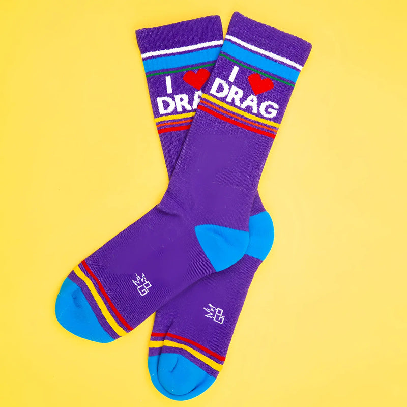 Purple crew socks with text and rainbow stripes on yellow background backdrop.