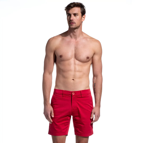 Shirtless man standing against a white background wearing bright red shorts.