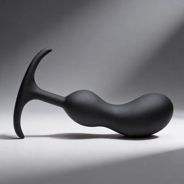 A smooth matte black curved silicone object sits on a grey surface.