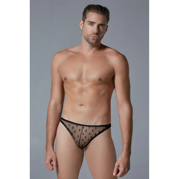 A man wears black sheer star-patterned thong underwear against grey background.