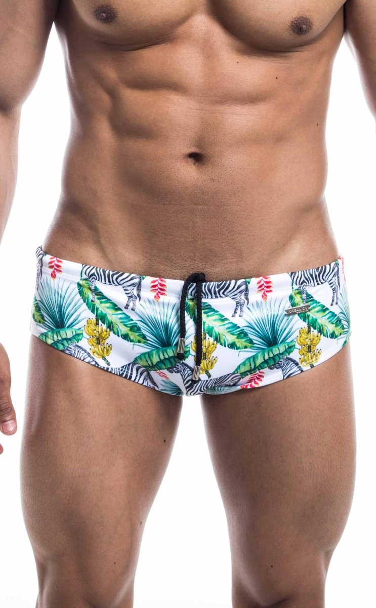 White swim trunks from oceanico swimwear featuring vibrant tropical print with green palm leaves yellow flowers and zebras