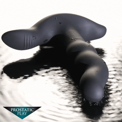 Matte black, twisted silicone object sitting on a reflective, rippling water surface.