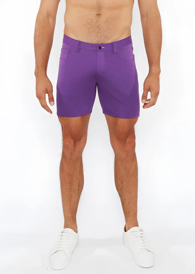 Shirtless man wearing purple shorts and white sneakers against white background.