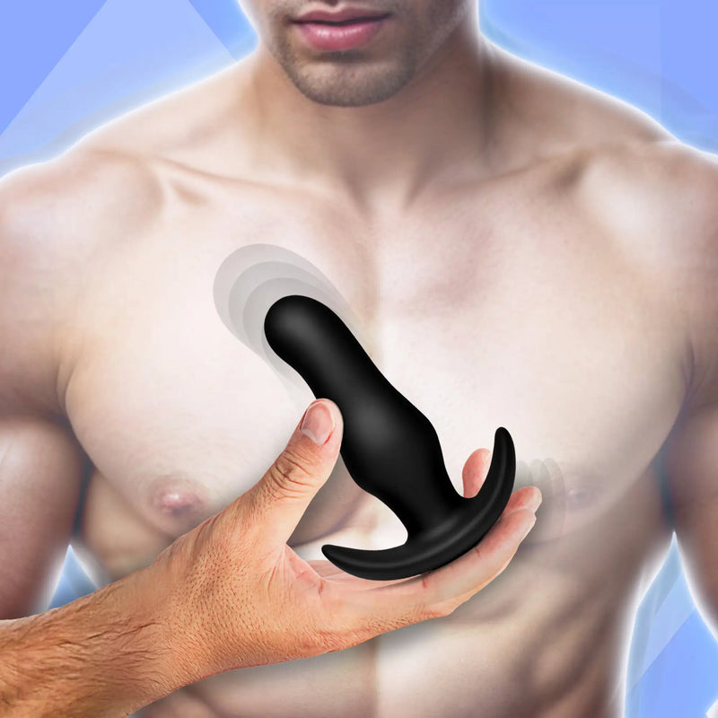 Hand holding a smooth black silicone object over a bare male torso.