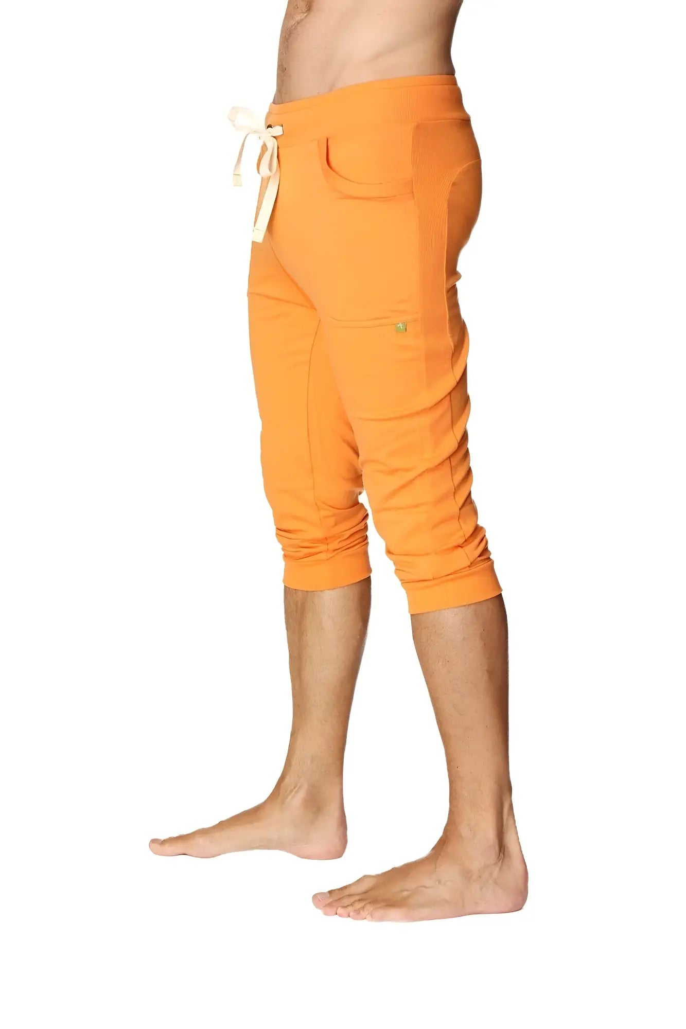 Mens cuffed yoga pants in solid sun orange with white drawstring waistband and multiple pockets in capri length