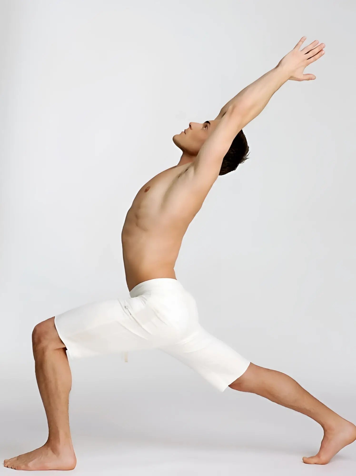 A man wearing white eco-track shorts made of sustainable fabric in a dynamic yoga stretching pose