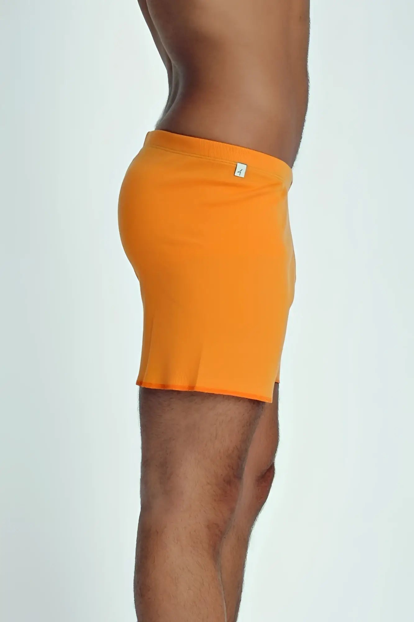 Bright orange ribbed men’s fusion yoga shorts with small white logo on waistband designed for active wear