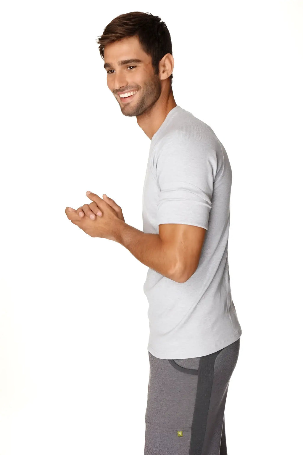 A man wearing a heather grey hybrid crew neck raglan tee with subtle texture and dark grey athletic pants with stripes