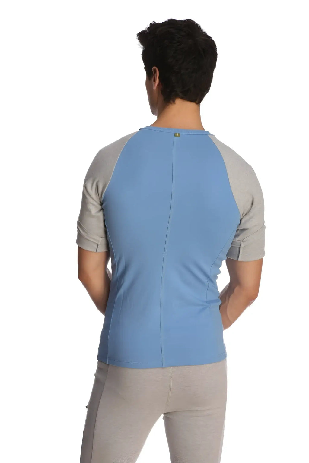 Back view of a light blue and gray raglan-sleeved athletic crew neck shirt with a subtle vertical seam down the back