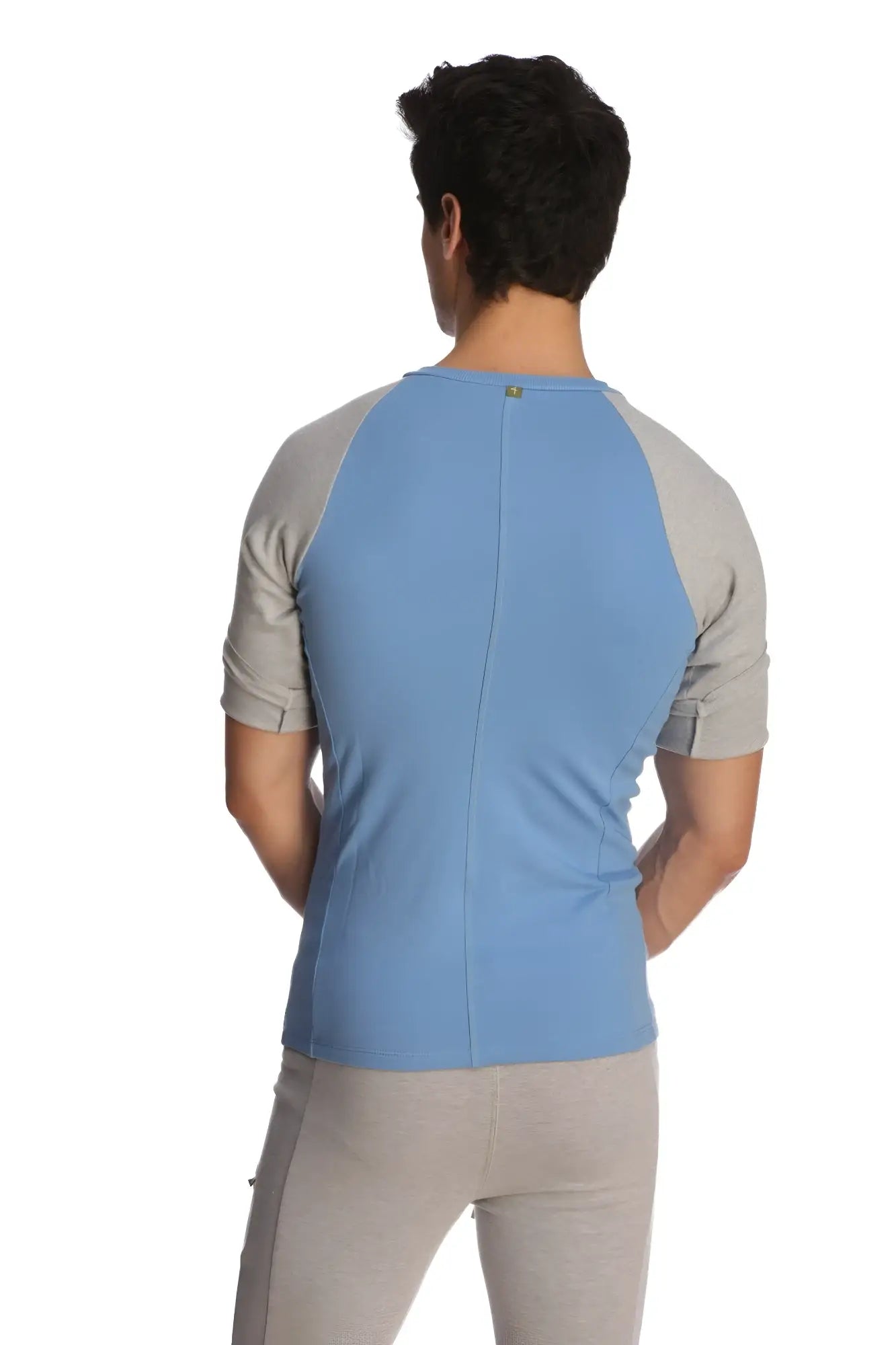 Back view of a light blue and gray raglan-sleeved athletic crew neck shirt with a subtle vertical seam down the back
