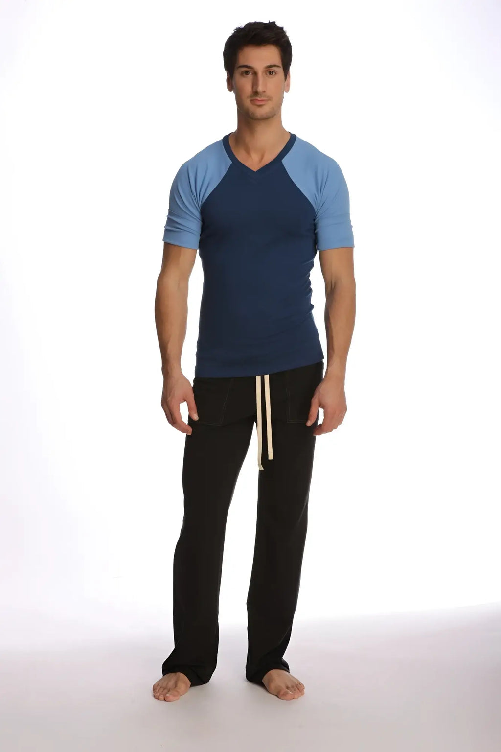 Man wearing a raglan virtual crew neck t-shirt in royal blue with black pants featuring cream drawstrings