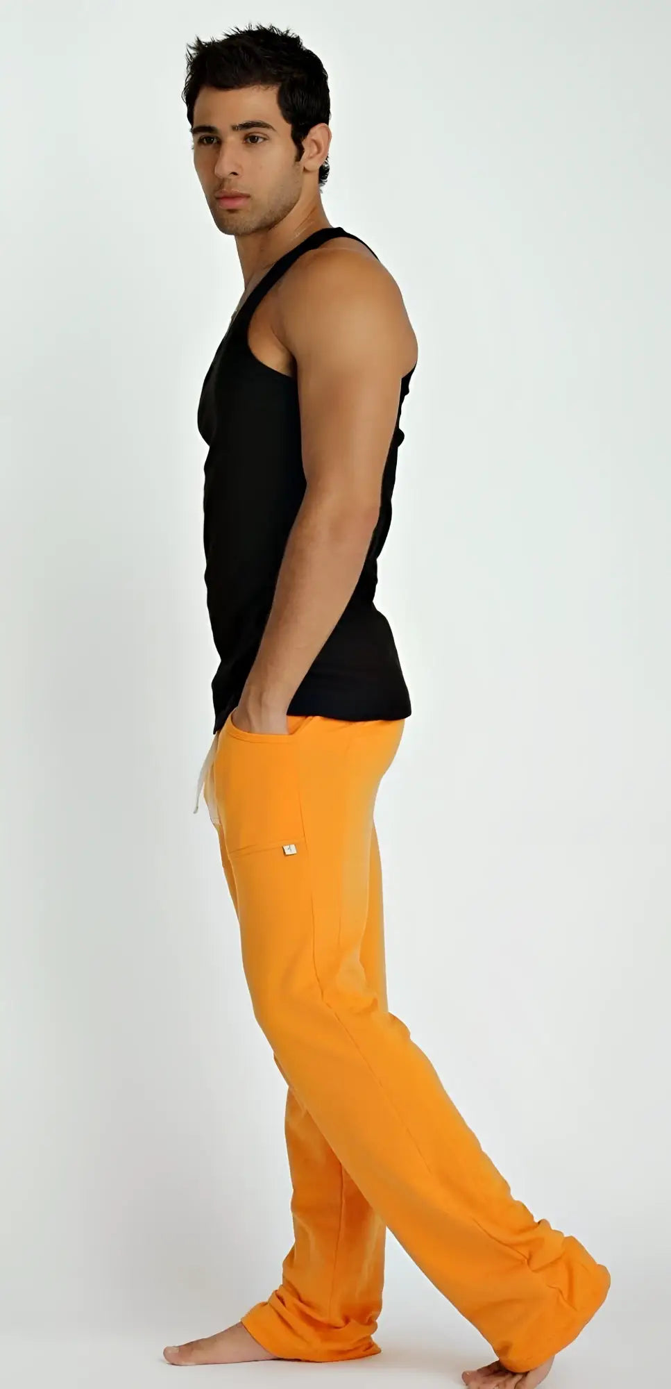 Bright orange loose-fitting pants with a small white logo on the thigh paired with a black sustain tank top