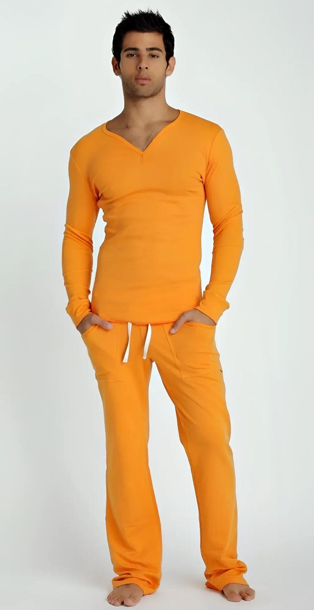 A man wearing a vibrant sun orange thermal v-neck long sleeve top and matching pants with white drawstrings