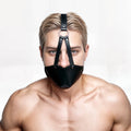 A shirtless man wears a black leather Strict Muzzle Harness with a concealed ball gag against a white background.