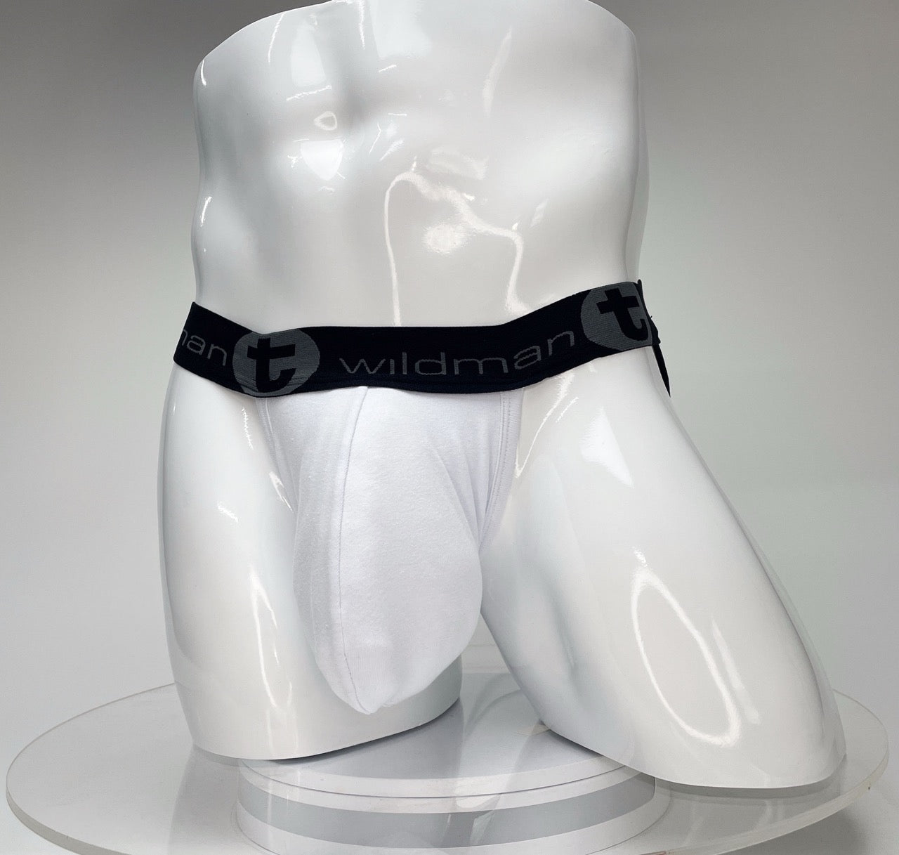 White WildmanT Big Boy pouch jockstrap on a mannequin, featuring a black waistband with WildmanT logo branding.