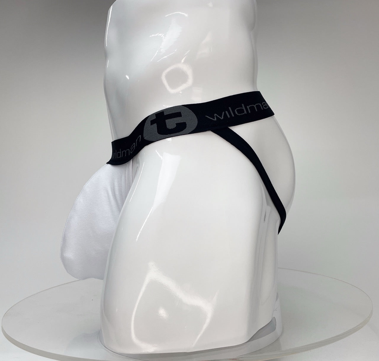 WildmanT Big Boy white jockstrap with a large pouch and black branded elastic waistband on a white mannequin.