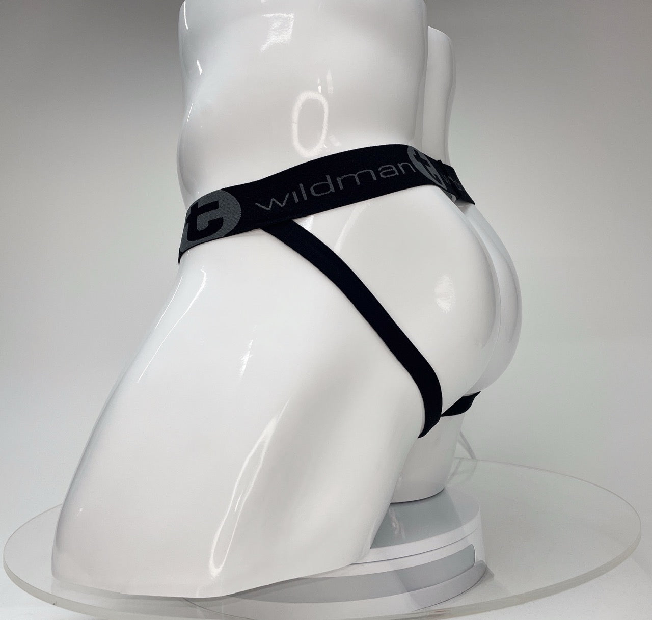 WildmanT Big Boy white jockstrap on a white mannequin featuring a black elastic waistband with brand logo branding.