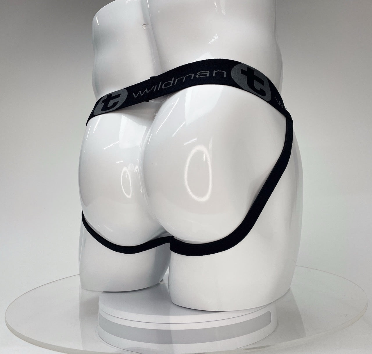 White jockstrap on a glossy mannequin torso, featuring a black waistband with the "WildmanT" logo.