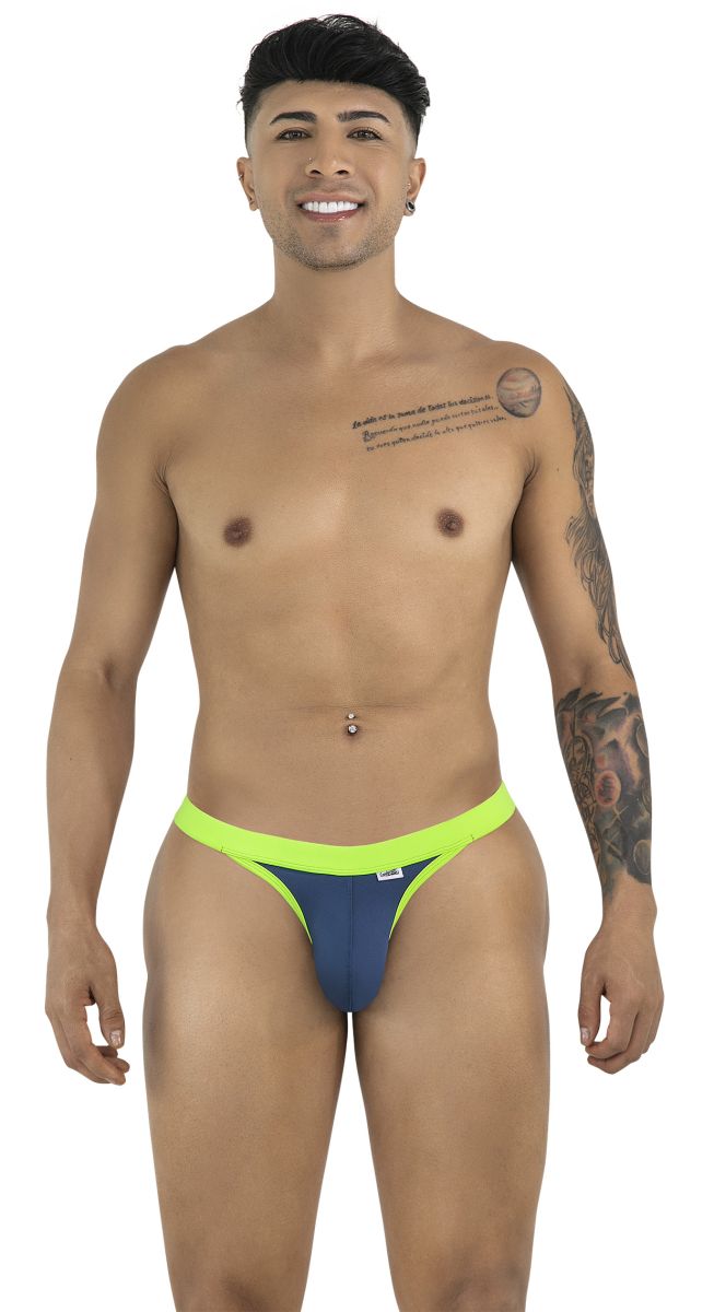A smiling man wearing navy blue CandyMan thongs with neon green trim, standing against a white background.