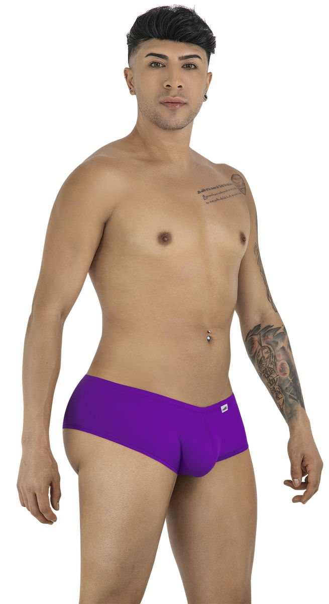 A man posing in CandyMan orchid purple trunks, showing a side-front profile against a plain white background.
