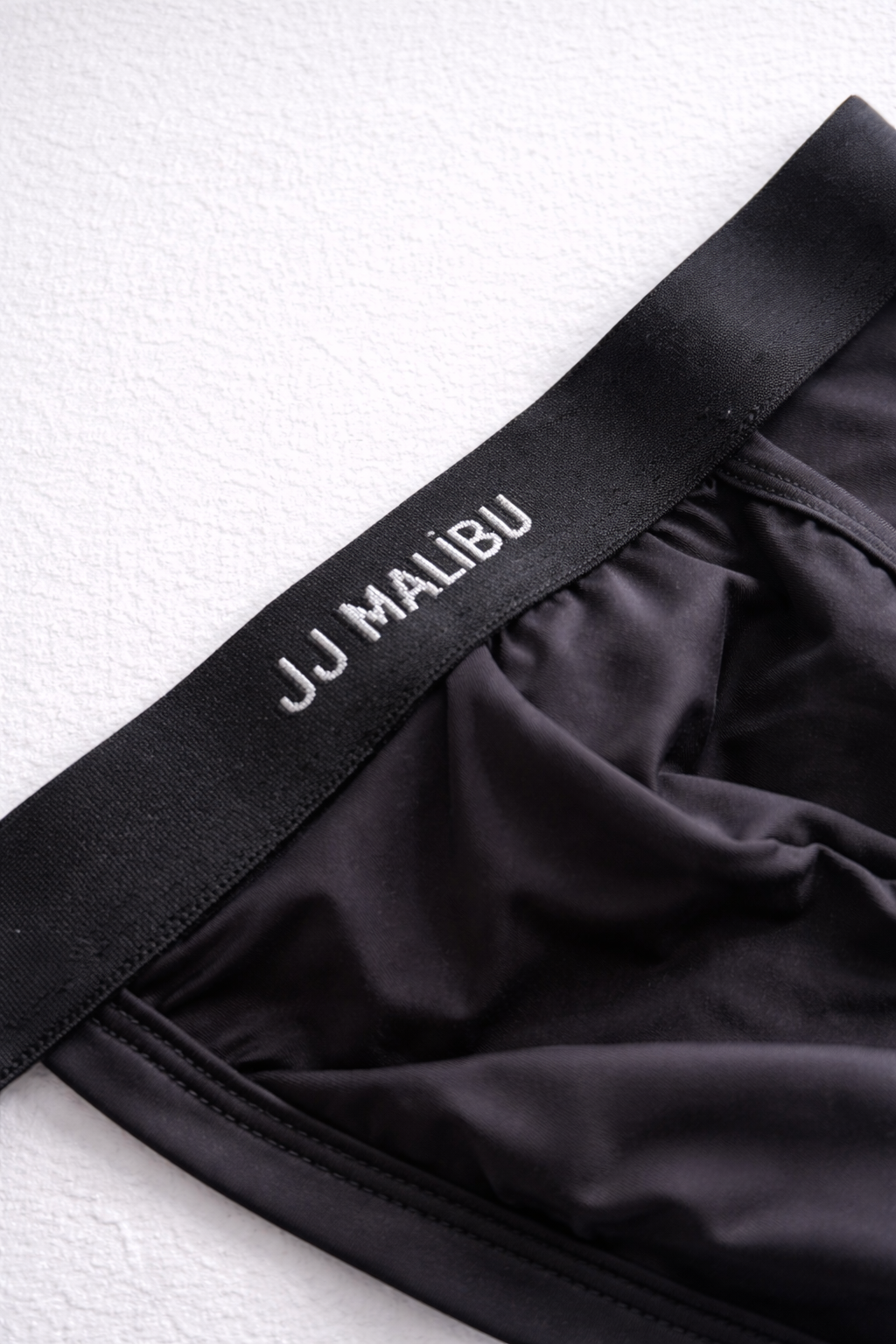 Black Host-or-Travel adjustable jock thong made of smooth stretchy fabric with white embroidered waistband branding
