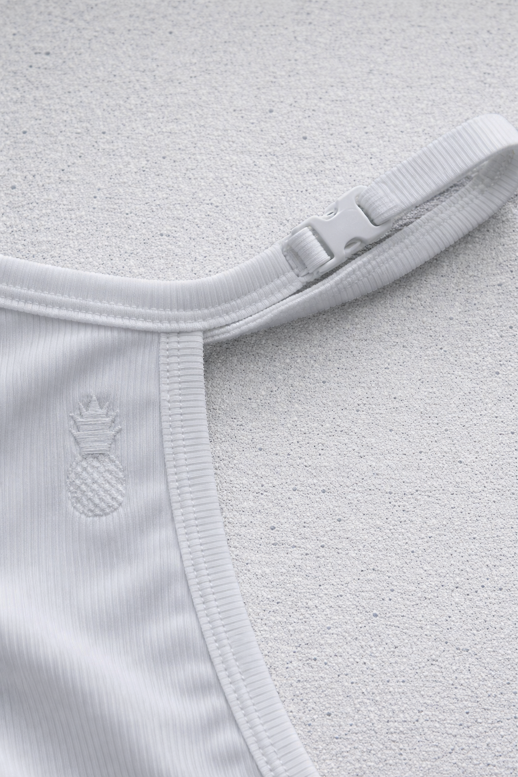 White ribbed fabric strap with plastic buckle and embroidered pineapple detail on the back of polar white g string v back jockstrap