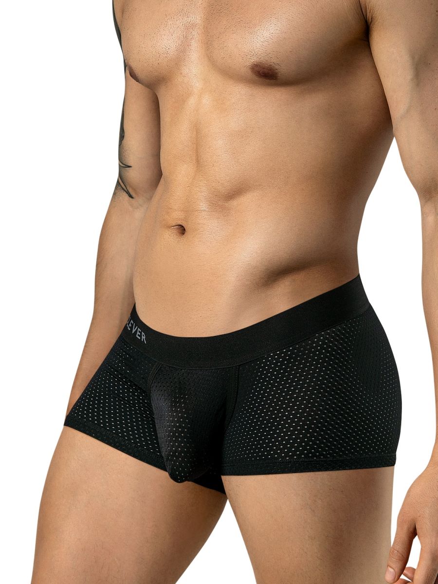 A model wearing black mesh trunks with a wide, branded waistband from a low three-quarter angle.