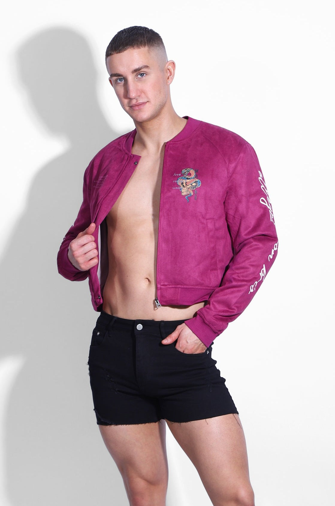 A vibrant magenta cropped suede bomber jacket with an embroidered dragon chest design and white sleeve lettering