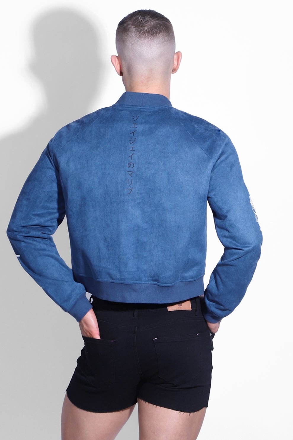 Back view of navy cropped suede bomber jacket with blue suede and vertical lettering down the back