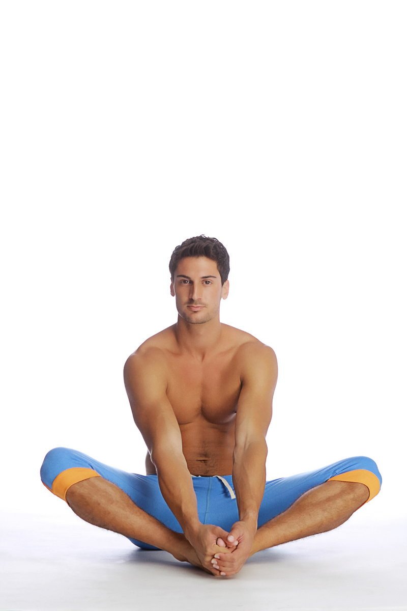 A man wearing cuffed yoga pants in ice blue with orange accents on the cuffs for athletic use