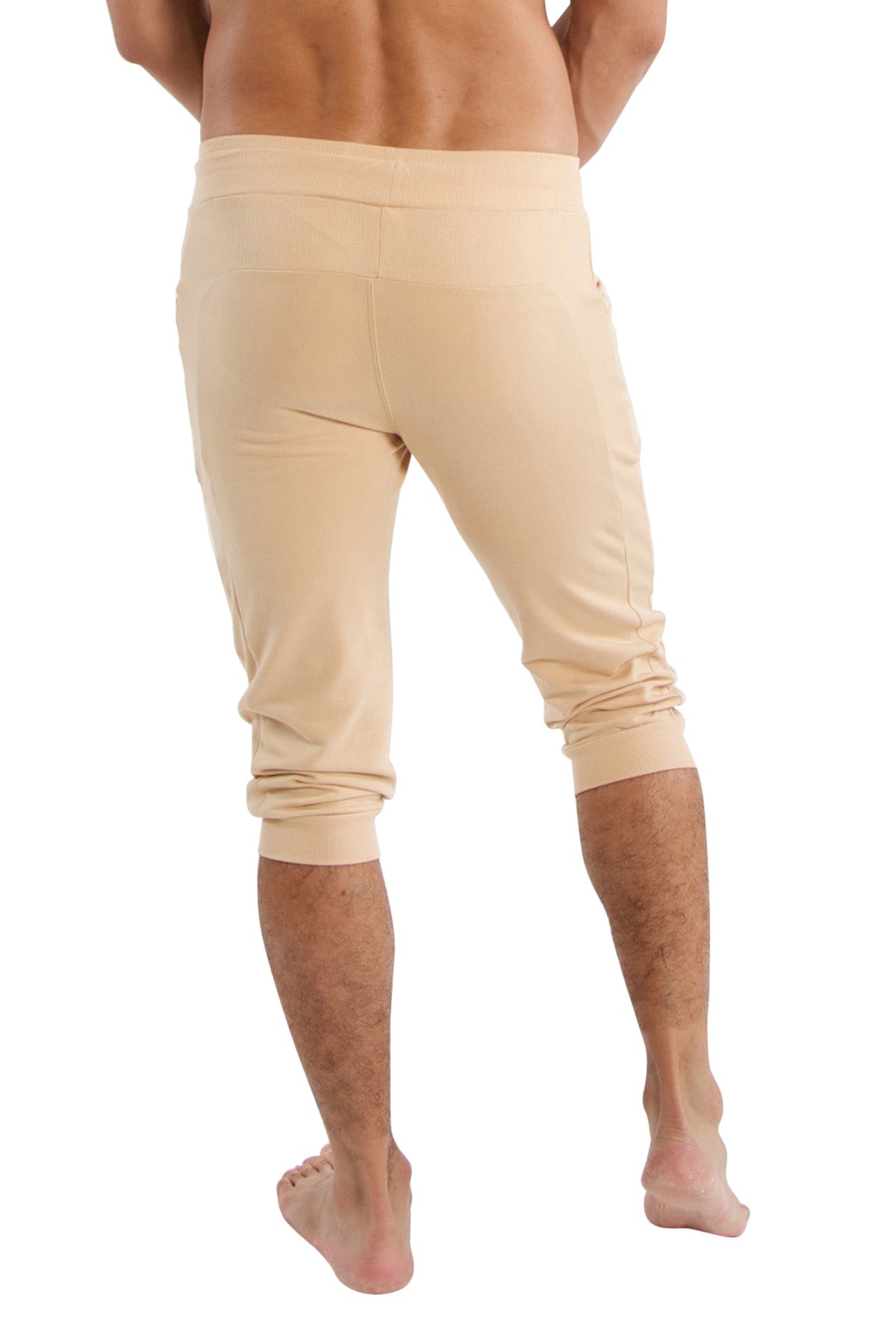 Beige cuffed yoga pants in soft stretchy fabric with rolled cuffs and capri-length fit for athletic wear