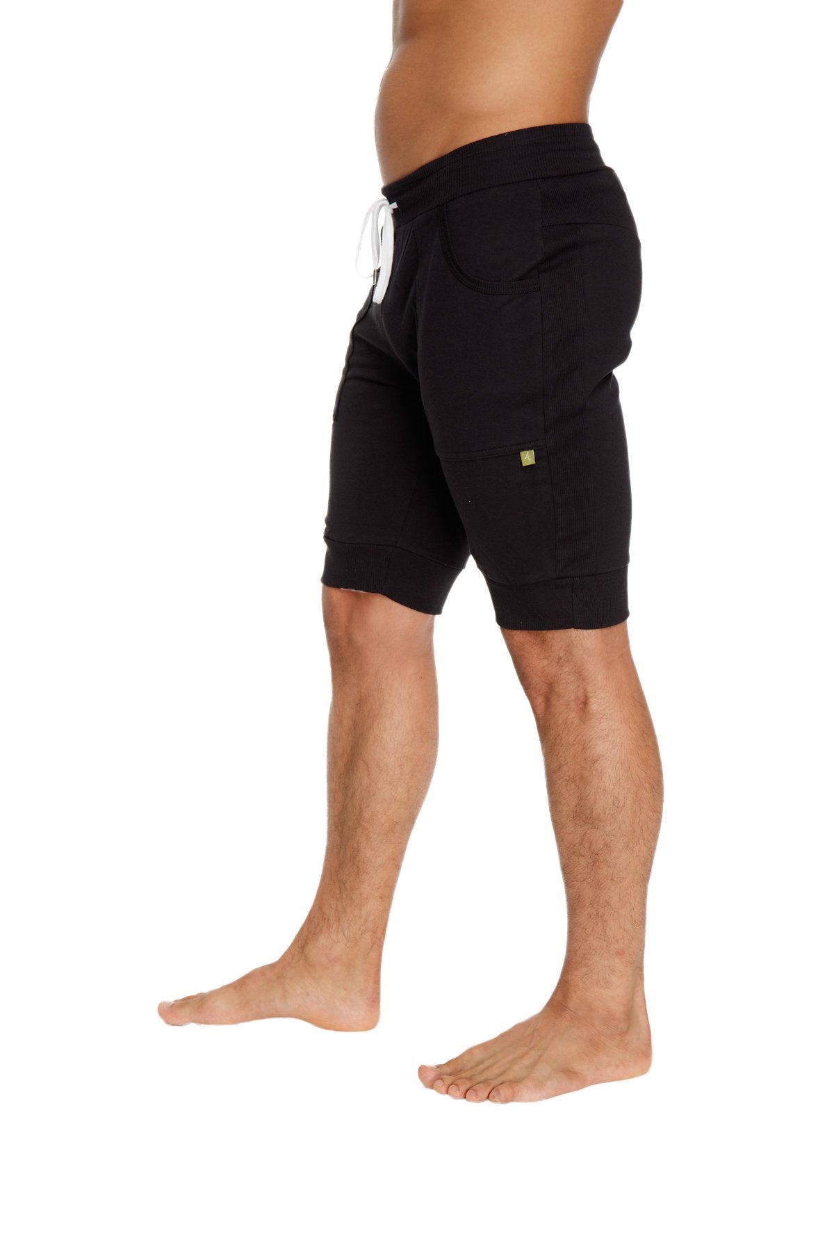 Black cuffed yoga shorts made of cotton with a white drawstring and small green logo on the side