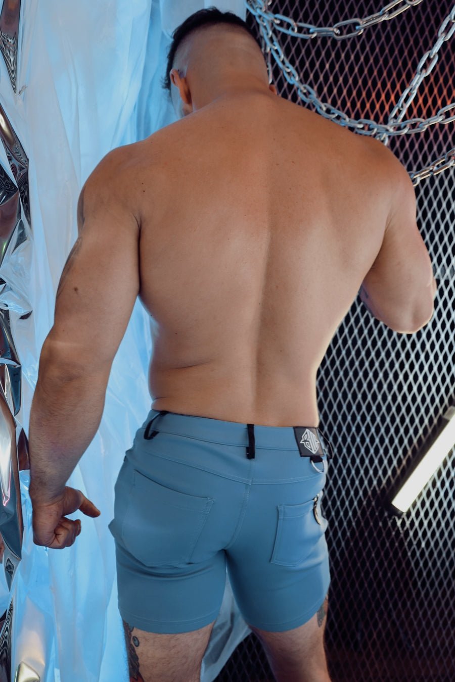 The back side of light blue down low shorts with a black belt loop and small logo patch on the waistband