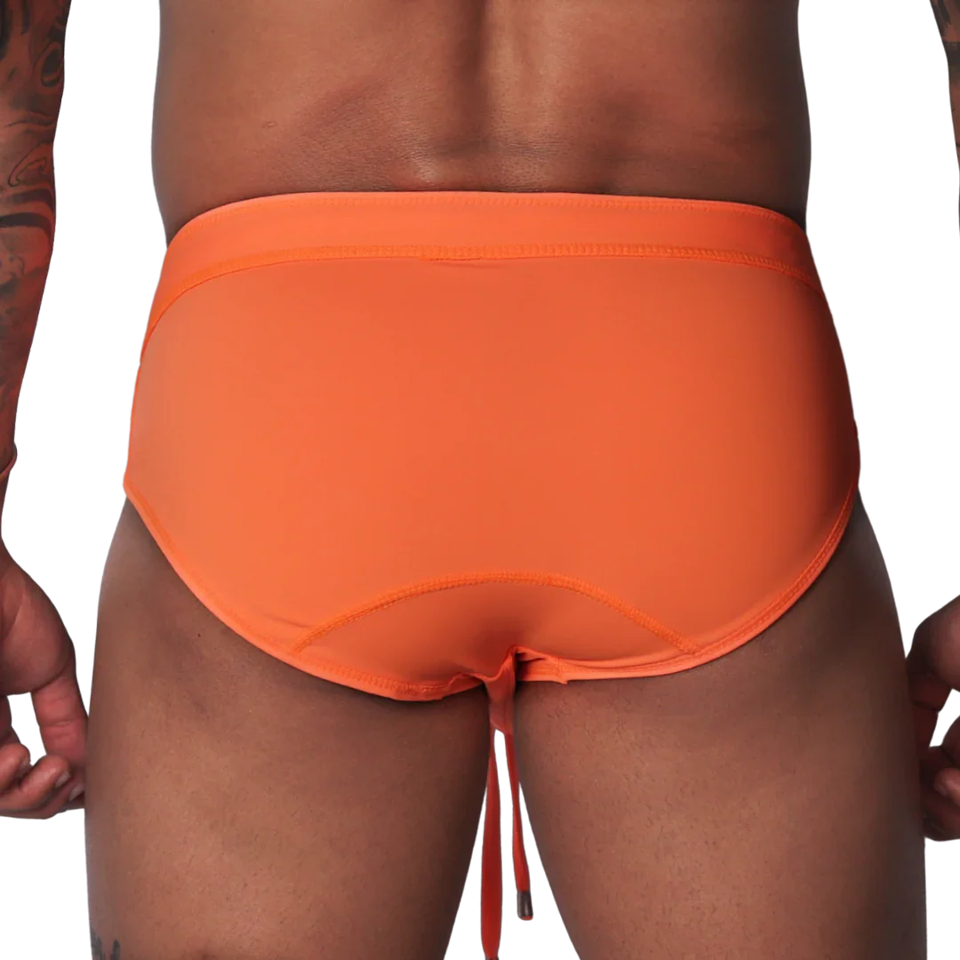Bright orange swim brief with a wide waistband, contoured back seams, and dangling drawstring against black background.