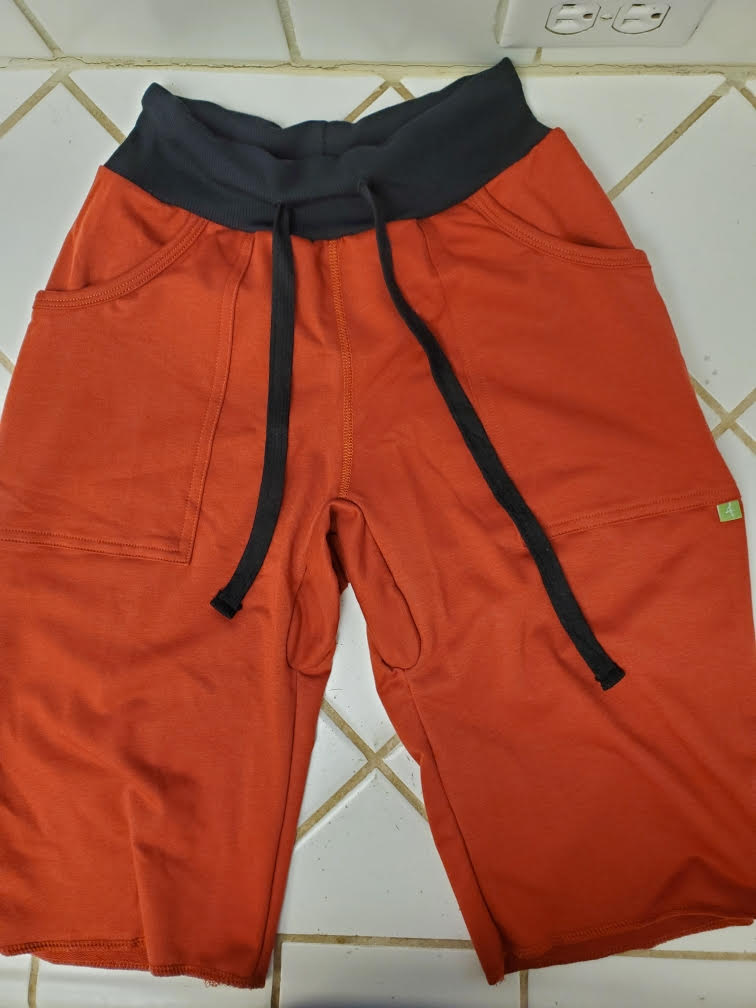 Eco-track short cinnabar orange athletic shorts with black waistband drawstrings side pockets and green brand tag on thigh