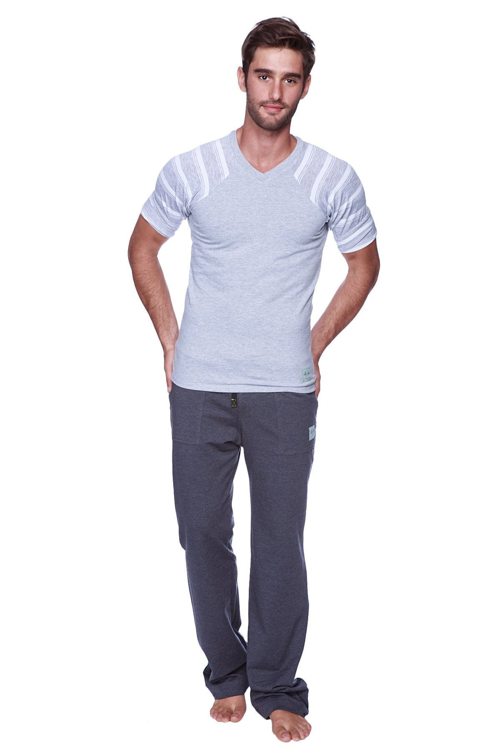 A man wearing a light gray v-neck t-shirt with white stripes paired with solid charcoal eco-track and yoga sweat pants