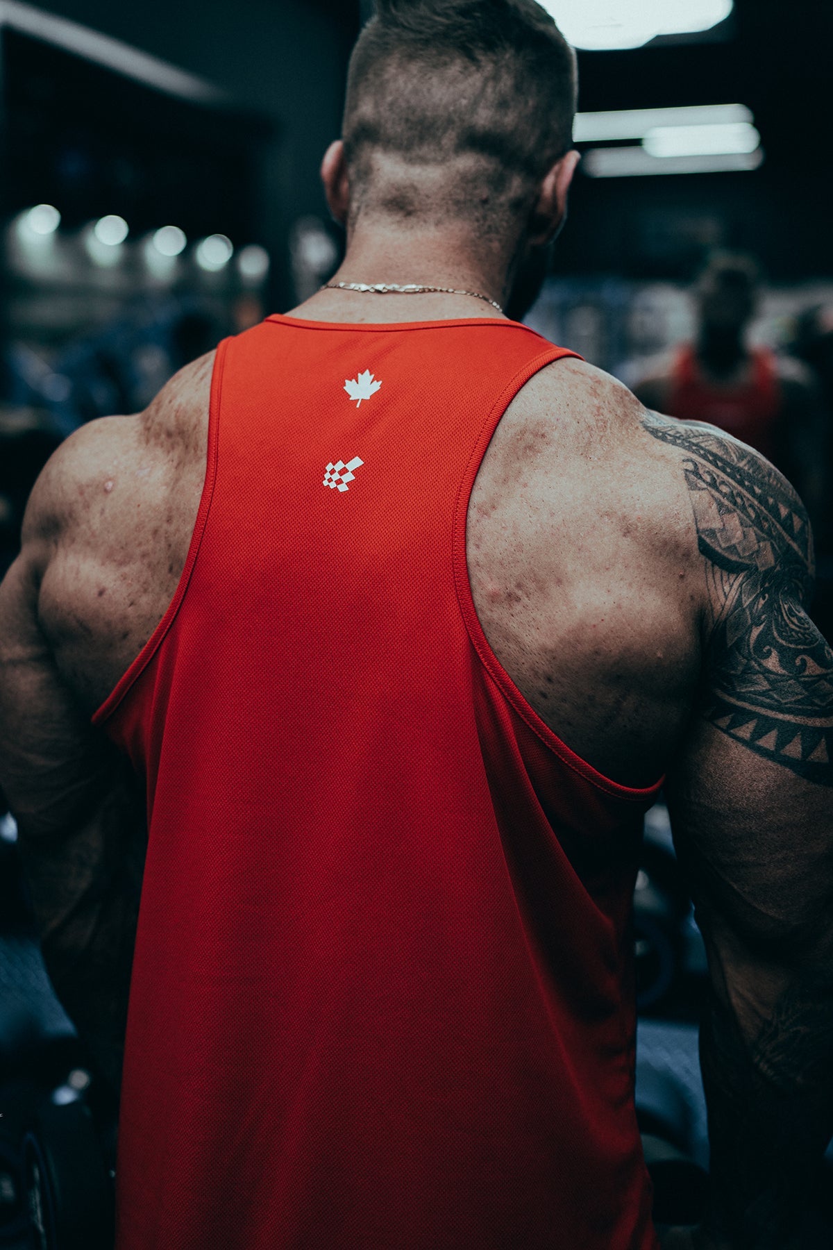 Back view of red fast-dry bodybuilding stringer with white maple leaf and logo emblem for workout use
