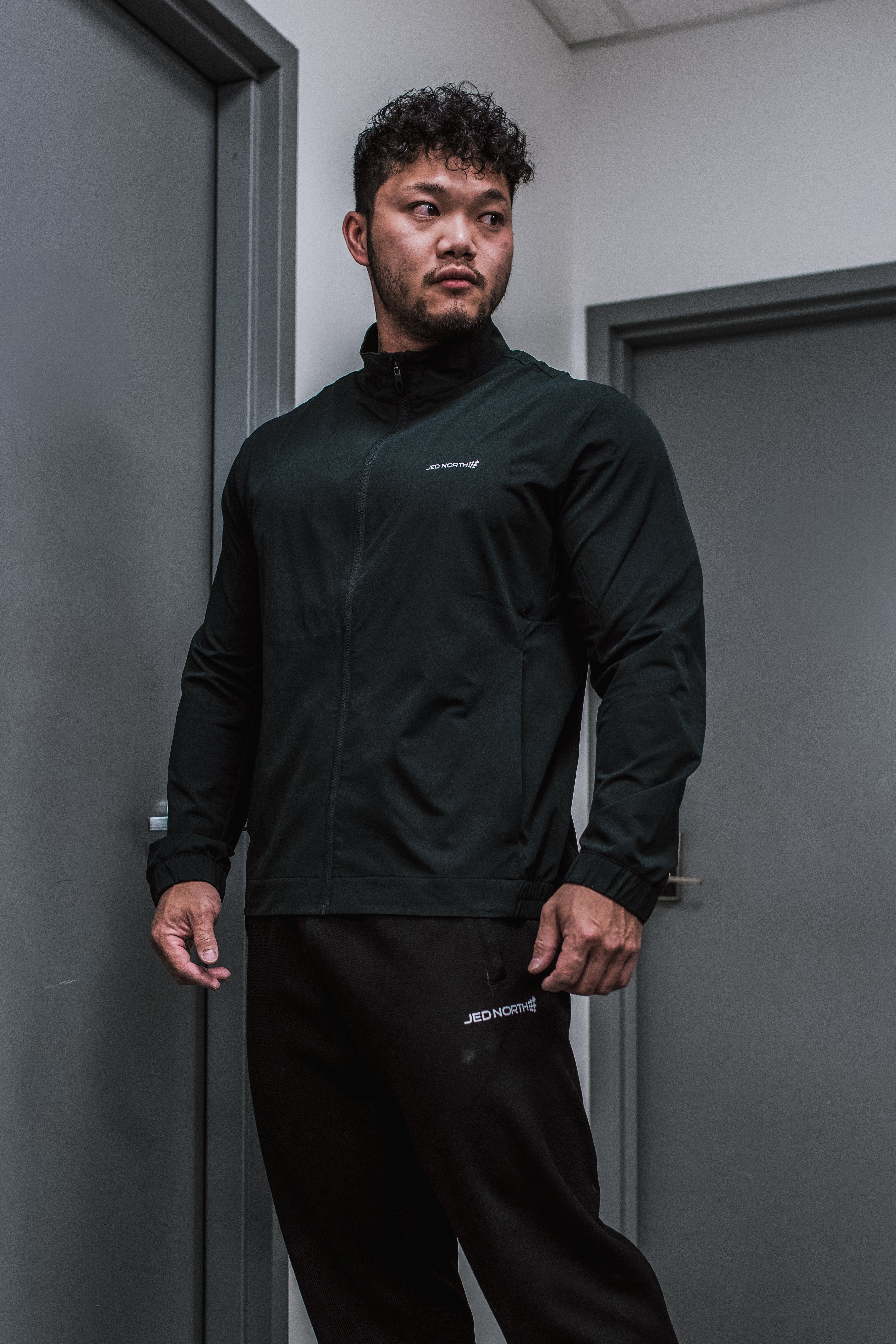 Black full-zip training jacket with subtle white branding on chest and sleeve perfect for athletic use