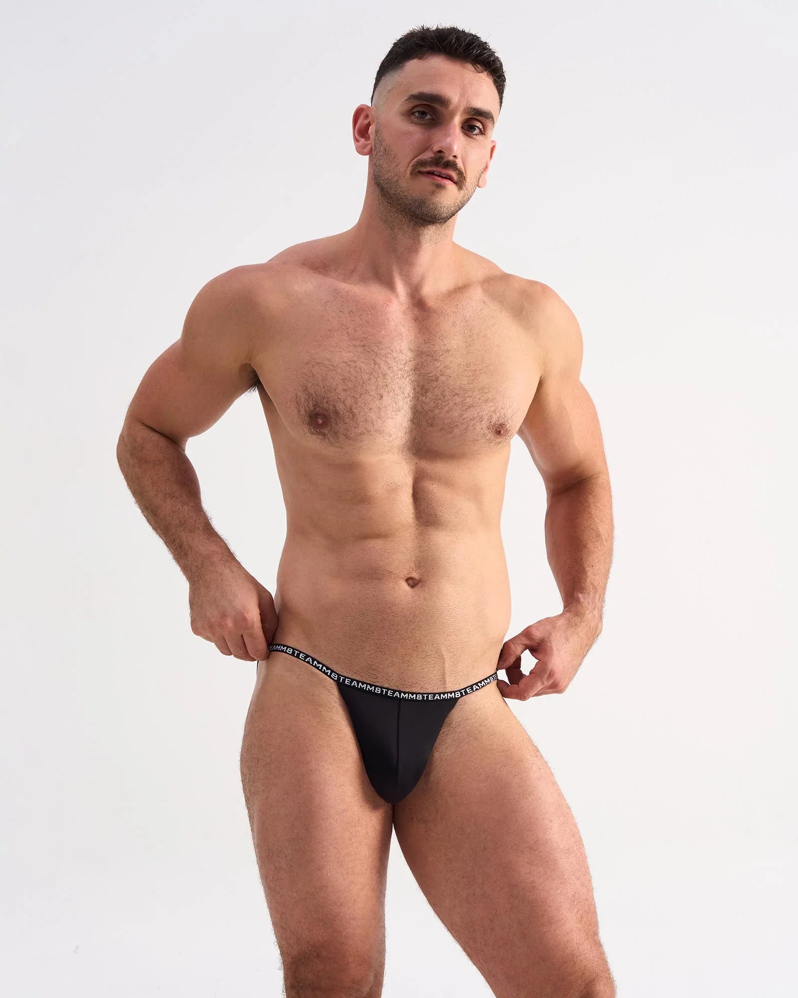 Black glide micro brief thong with white repeating logo waistband showing the back side of the underwear