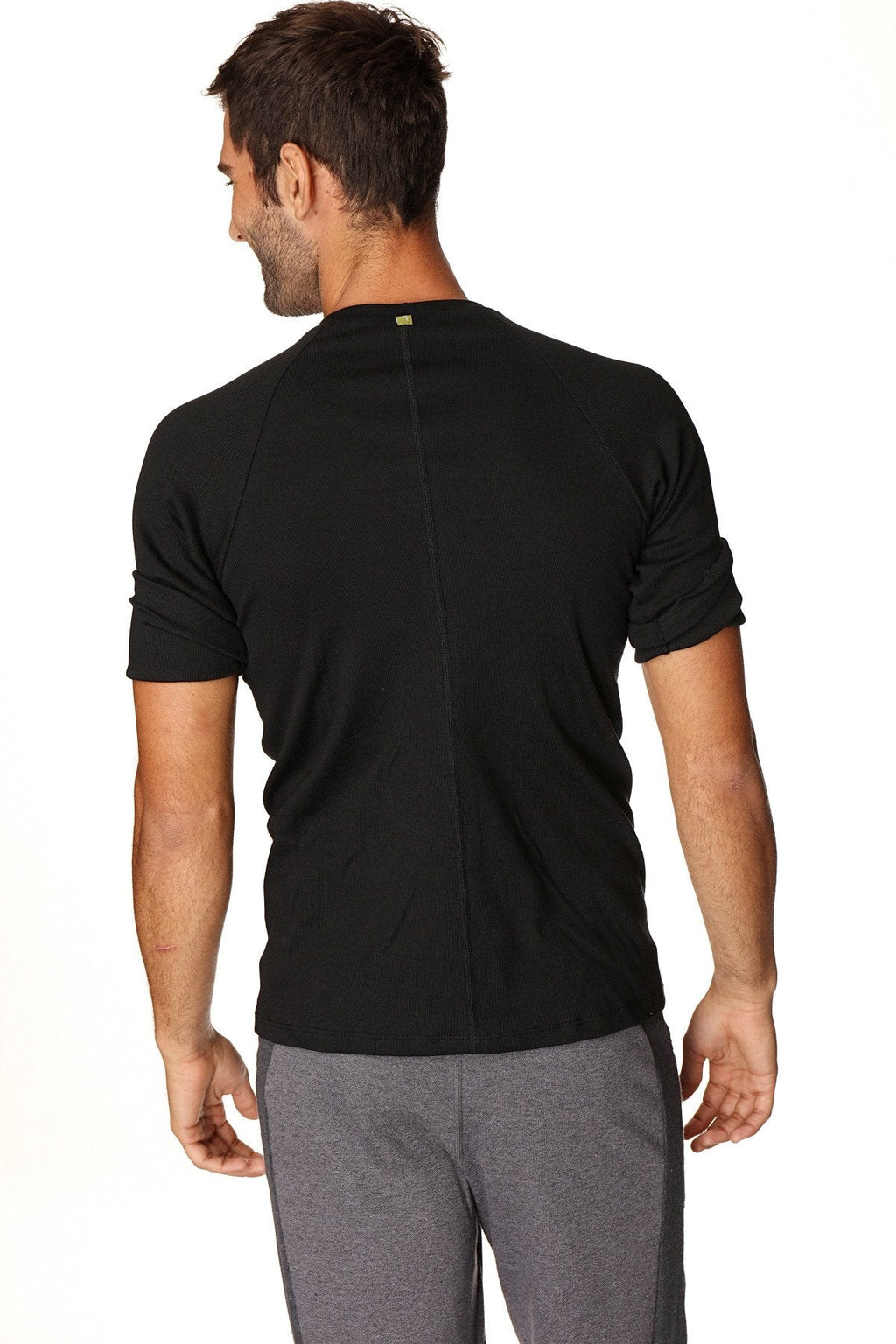 Back view of hybrid crew neck raglan tee black short-sleeved athletic shirt with vertical seam and green logo