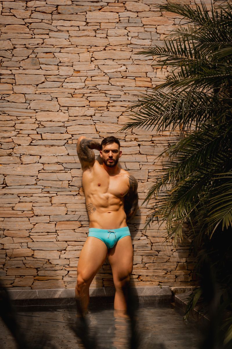 A man wearing bright turquoise jor 2387 travel swim briefs with a simple drawstring waistband for swimming and travel