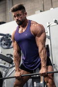 A muscular man wearing a violet jed north fast-dry bodybuilding workout stringer and black shorts gripping a barbell
